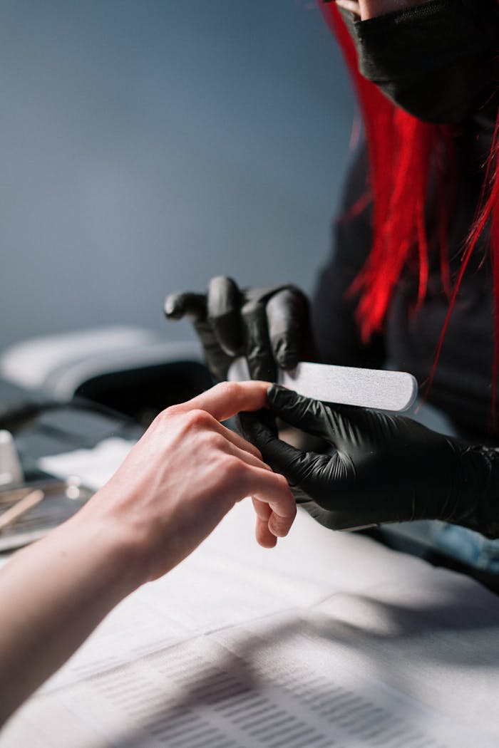 portfolio-05 Close-up of a professional manicurist providing nail care with black gloves.