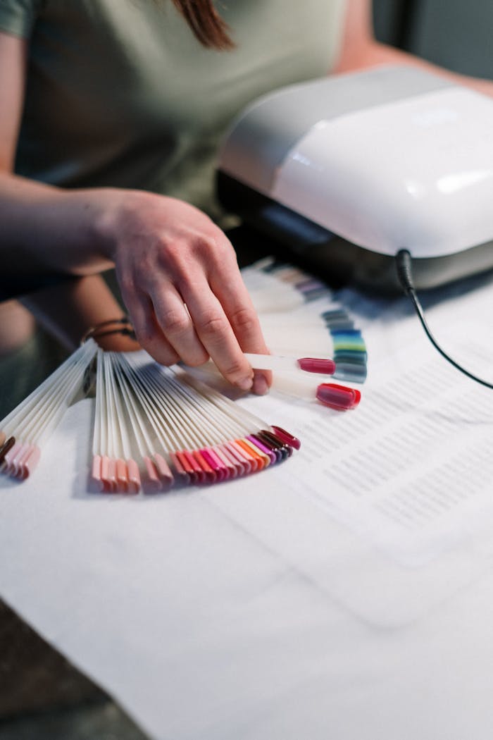 why-choose-us Close-up of a manicurist selecting nail polish colors in a salon setting.
